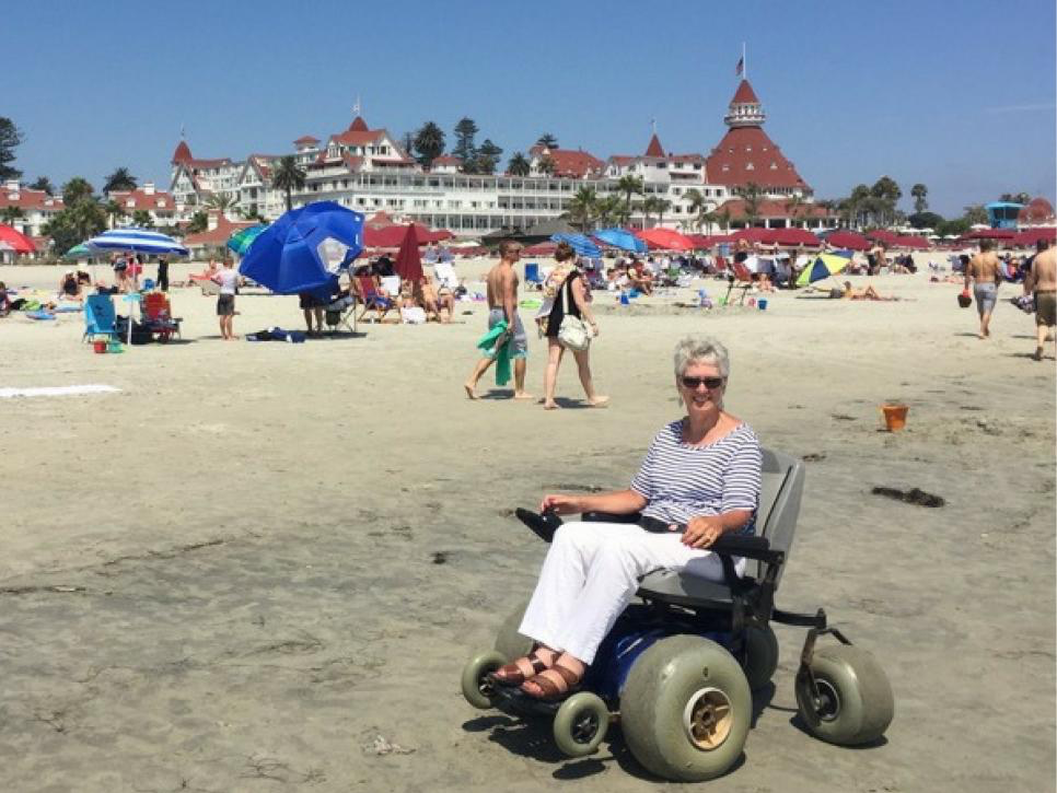 Happy woman in a beach wheelchair on Coronado Beach